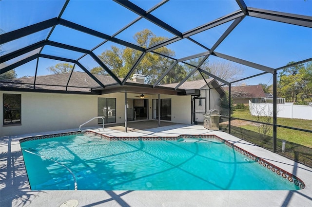 pool featuring glass enclosure, a patio, fence, and a ceiling fan