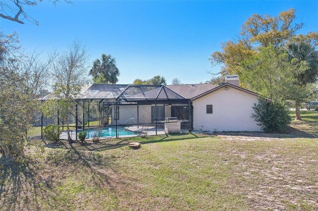 back of house with glass enclosure, a yard, an outdoor pool, a chimney, and stucco siding