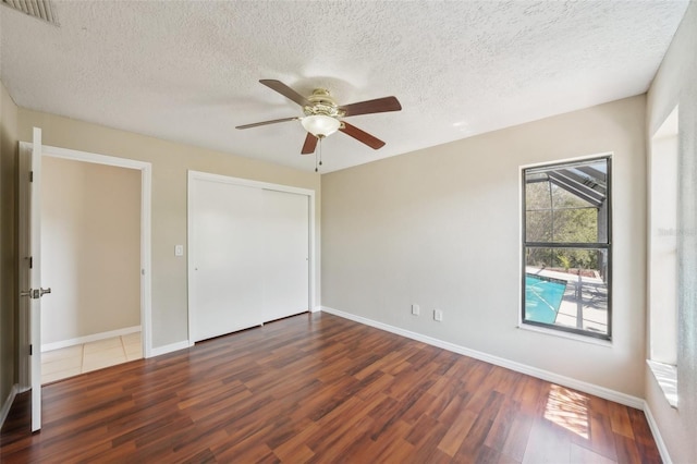 14048 Bruni Dr, Spring Hill, FL 34609 - unfurnished bedroom with wood finished floors, a textured ceiling, a closet, and a ceiling fan