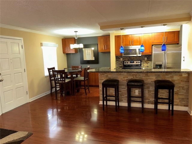 kitchen featuring stainless steel appliances, a kitchen bar, dark wood finished floors, and crown molding