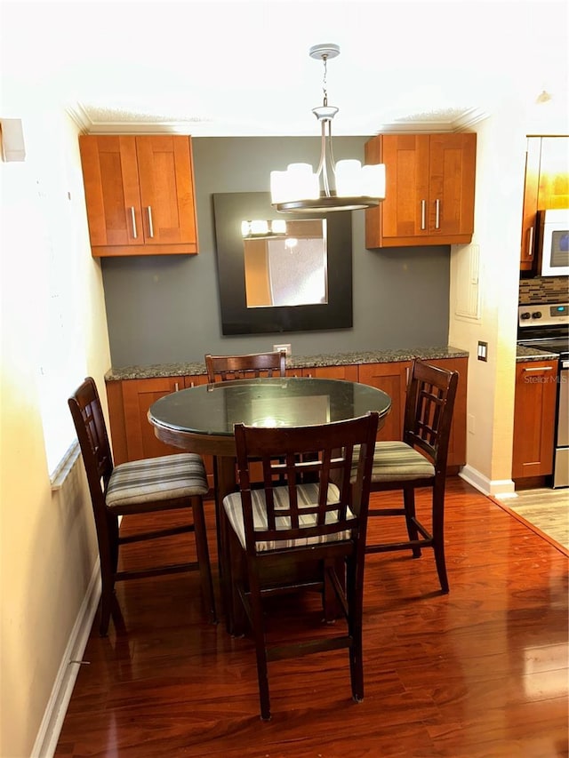 dining room featuring a notable chandelier, baseboards, and wood finished floors