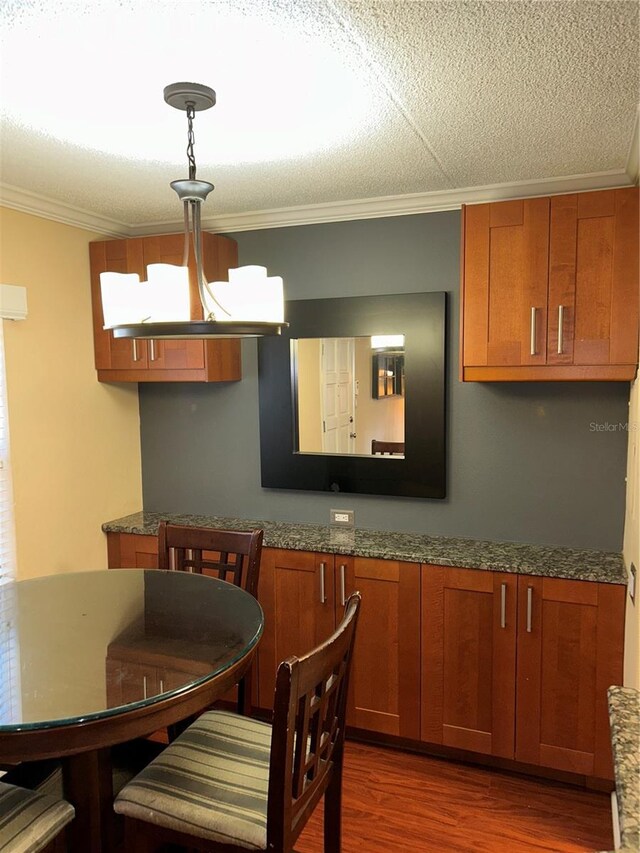 dining room with dark wood-style floors, a textured ceiling, and ornamental molding