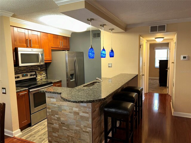 kitchen with a breakfast bar, a peninsula, visible vents, and appliances with stainless steel finishes