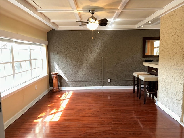 unfurnished room with wood finished floors, baseboards, coffered ceiling, beam ceiling, and a textured wall