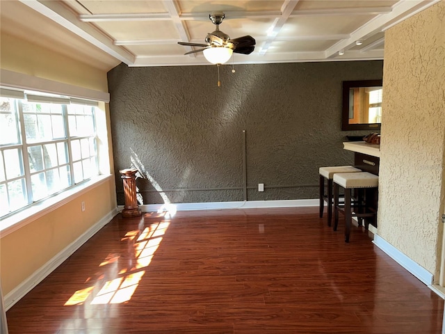 empty room with wood finished floors, baseboards, coffered ceiling, beam ceiling, and a textured wall