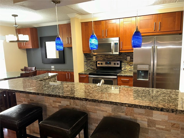 kitchen with crown molding, a breakfast bar, decorative backsplash, hanging light fixtures, and stainless steel appliances