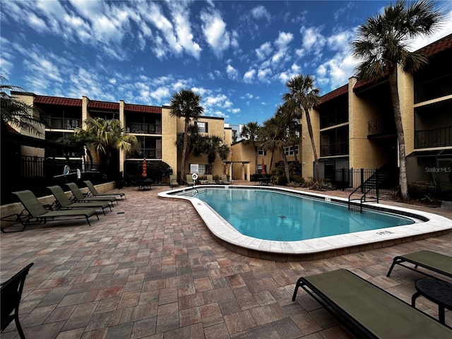 pool with a patio area and fence