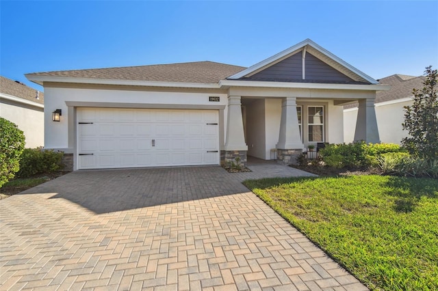 view of front of house featuring decorative driveway, stone siding, and stucco siding