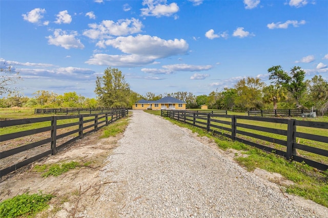 view of street featuring gravel driveway and a rural view