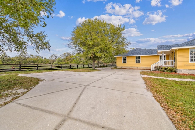 exterior space featuring fence, a lawn, and driveway