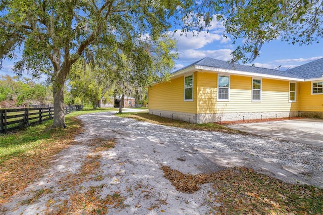 view of property exterior with roof with shingles, driveway, and fence