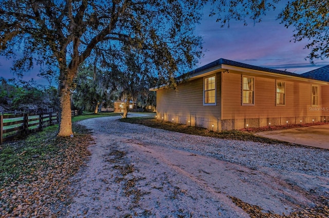 view of side of property with gravel driveway and fence