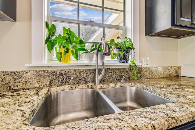 room details featuring a sink and light stone countertops