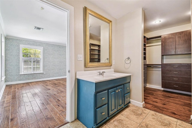 bathroom featuring visible vents, baseboards, wood finished floors, and wallpapered walls