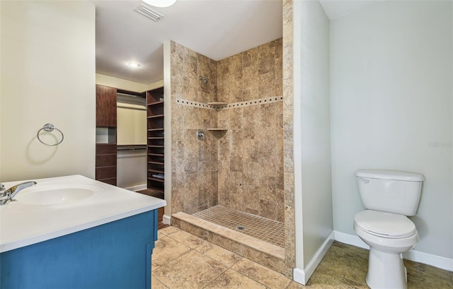 full bath with visible vents, toilet, a tile shower, baseboards, and vanity