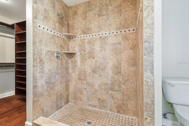 full bathroom featuring toilet, wood finished floors, a stall shower, and baseboards