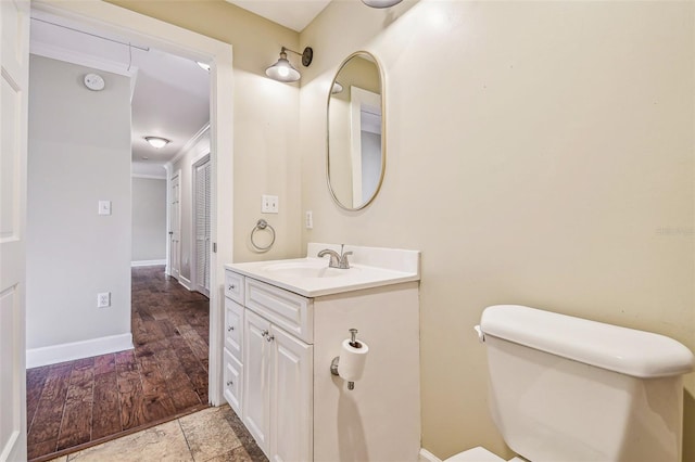 half bath featuring baseboards, toilet, and vanity