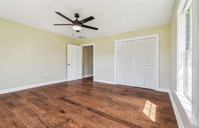 unfurnished bedroom with a closet, baseboards, and dark wood-type flooring