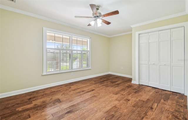 unfurnished bedroom featuring baseboards, dark wood finished floors, ornamental molding, a closet, and a ceiling fan