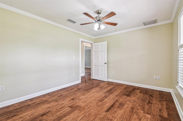 spare room with crown molding, wood finished floors, visible vents, and baseboards