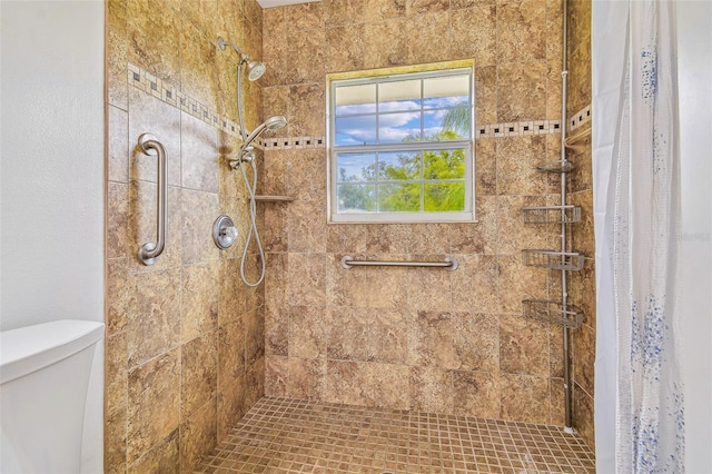 bathroom featuring tiled shower and toilet