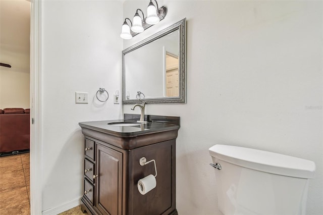 half bathroom with baseboards, toilet, and vanity