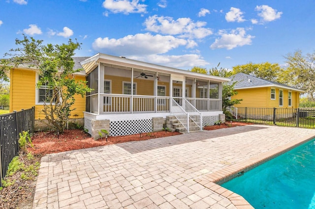 rear view of property featuring a fenced backyard, a fenced in pool, a sunroom, and ceiling fan