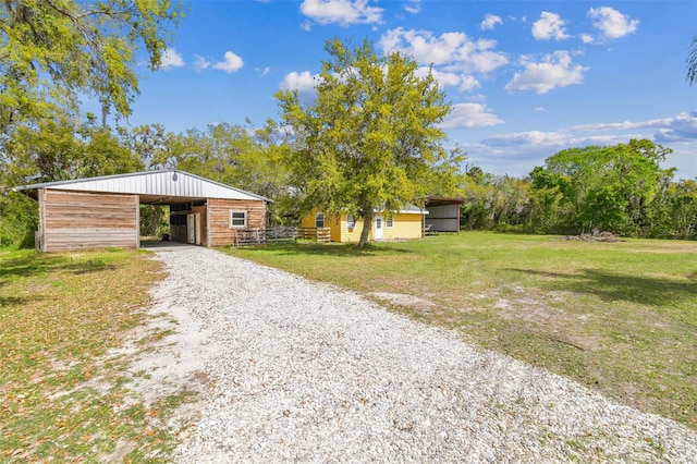 view of front facade featuring an outbuilding, driveway, a front lawn, and an outdoor structure