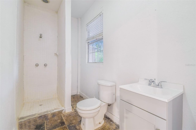 full bath with vanity, toilet, baseboards, and a tile shower