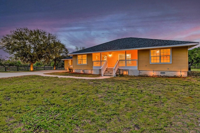 ranch-style home with a porch, fence, a yard, a shingled roof, and crawl space