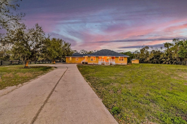 ranch-style house featuring a front lawn, fence, covered porch, an outdoor structure, and driveway