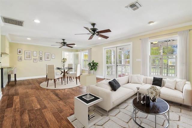 living room featuring visible vents, a healthy amount of sunlight, wood finished floors, and crown molding