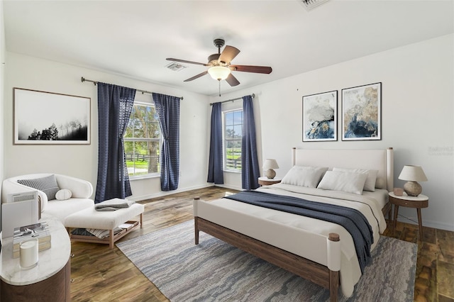 bedroom featuring a ceiling fan, wood finished floors, visible vents, and baseboards