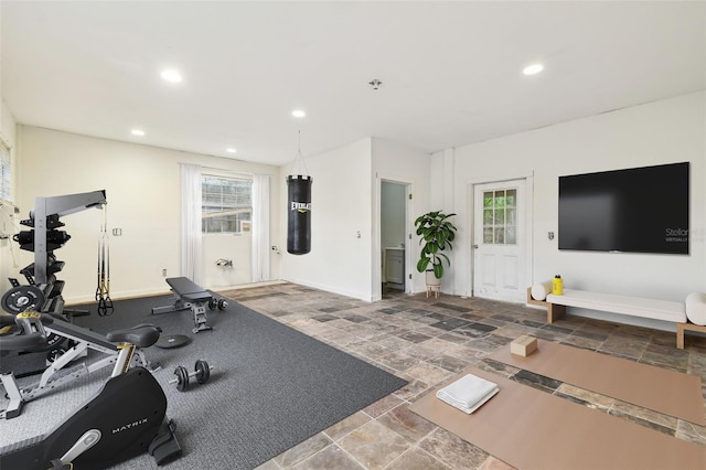 exercise area with recessed lighting, stone finish flooring, baseboards, and a healthy amount of sunlight