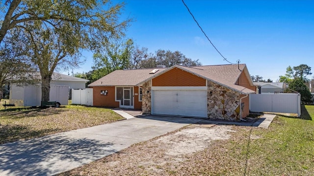 view of front of home with stone siding, fence, and concrete driveway