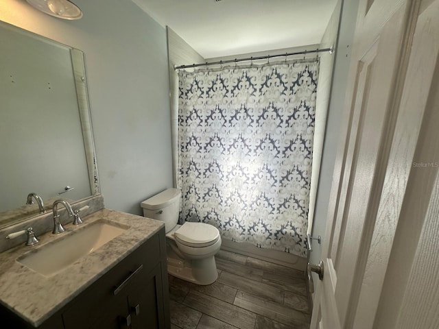 bathroom with wood finished floors, vanity, toilet, and shower / tub combo