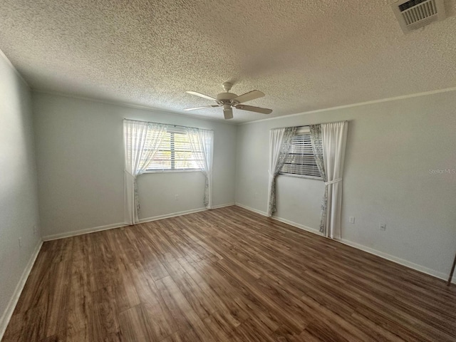 empty room featuring visible vents, a ceiling fan, a textured ceiling, wood finished floors, and baseboards