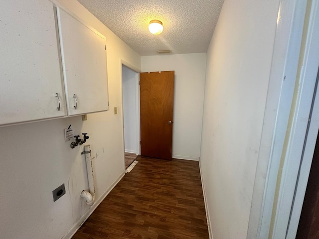 corridor with a textured ceiling, wood finished floors, visible vents, and baseboards