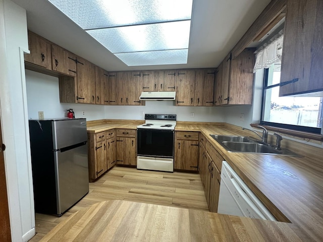 kitchen with electric range oven, freestanding refrigerator, a sink, white dishwasher, and extractor fan