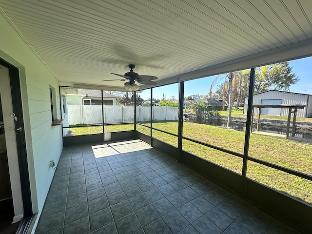 unfurnished sunroom with a ceiling fan and a water view