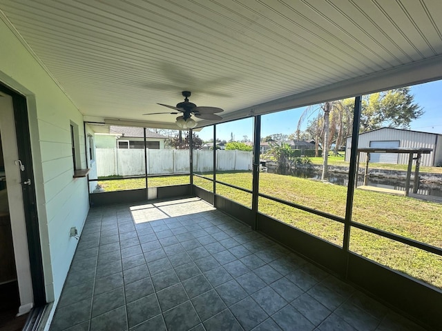 unfurnished sunroom featuring ceiling fan and a water view