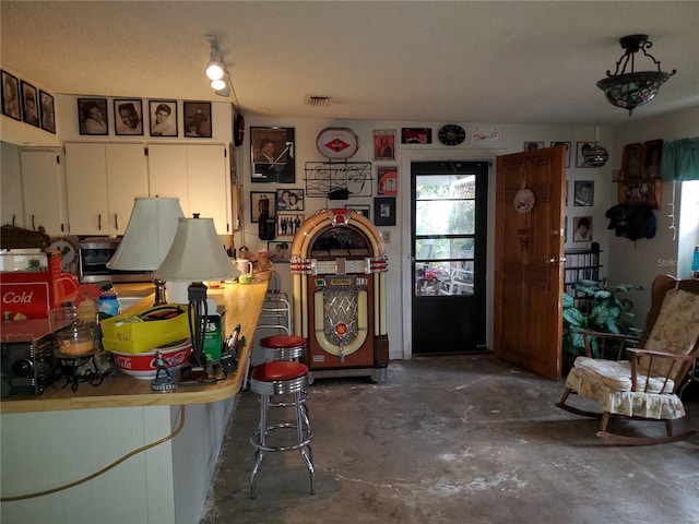 interior space featuring white cabinets, visible vents, and unfinished concrete floors