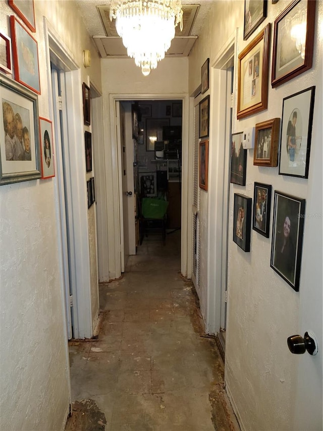 hallway featuring a textured wall and an inviting chandelier