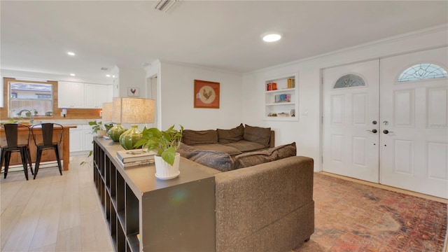 living area with recessed lighting, visible vents, crown molding, and light wood finished floors