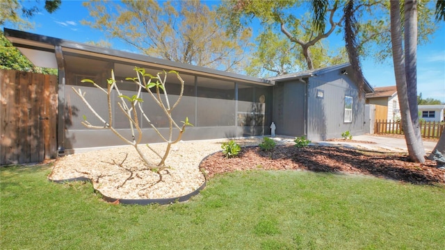 rear view of property with a sunroom, a lawn, and fence