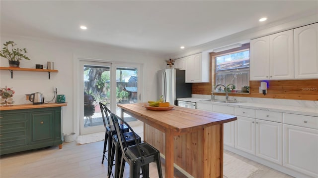 kitchen featuring wooden counters, appliances with stainless steel finishes, a sink, and white cabinetry