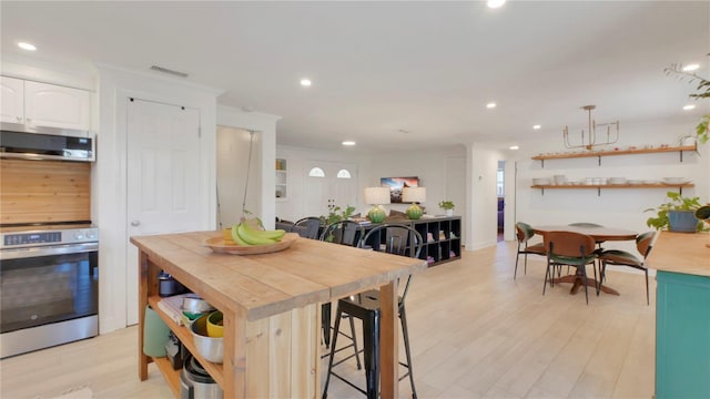 kitchen featuring stainless steel appliances, butcher block countertops, white cabinetry, and open shelves