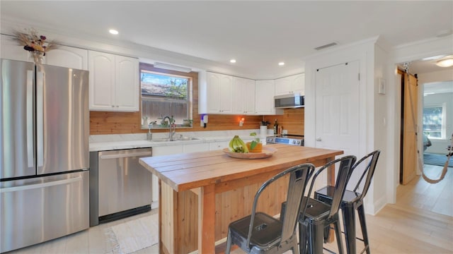 kitchen featuring stainless steel appliances, butcher block counters, visible vents, white cabinets, and a sink