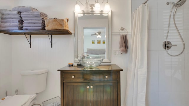 bathroom with a tile shower, vanity, toilet, and ceiling fan