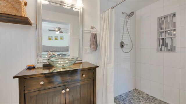 bathroom with tiled shower, vanity, and a ceiling fan